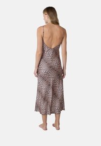 Abito in tessuto animalier con spacco profondo sulla schiena, spalline sottili e silhouette fluida. Realizzato in tessuto morbido con una texture liscia.