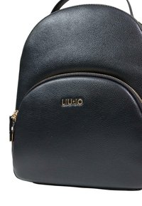 Sort læderrygsæk med rundet form, tekstureret overflade, guldhardware og en forside med lynlåslomme med mærket "LIU JO" logo.