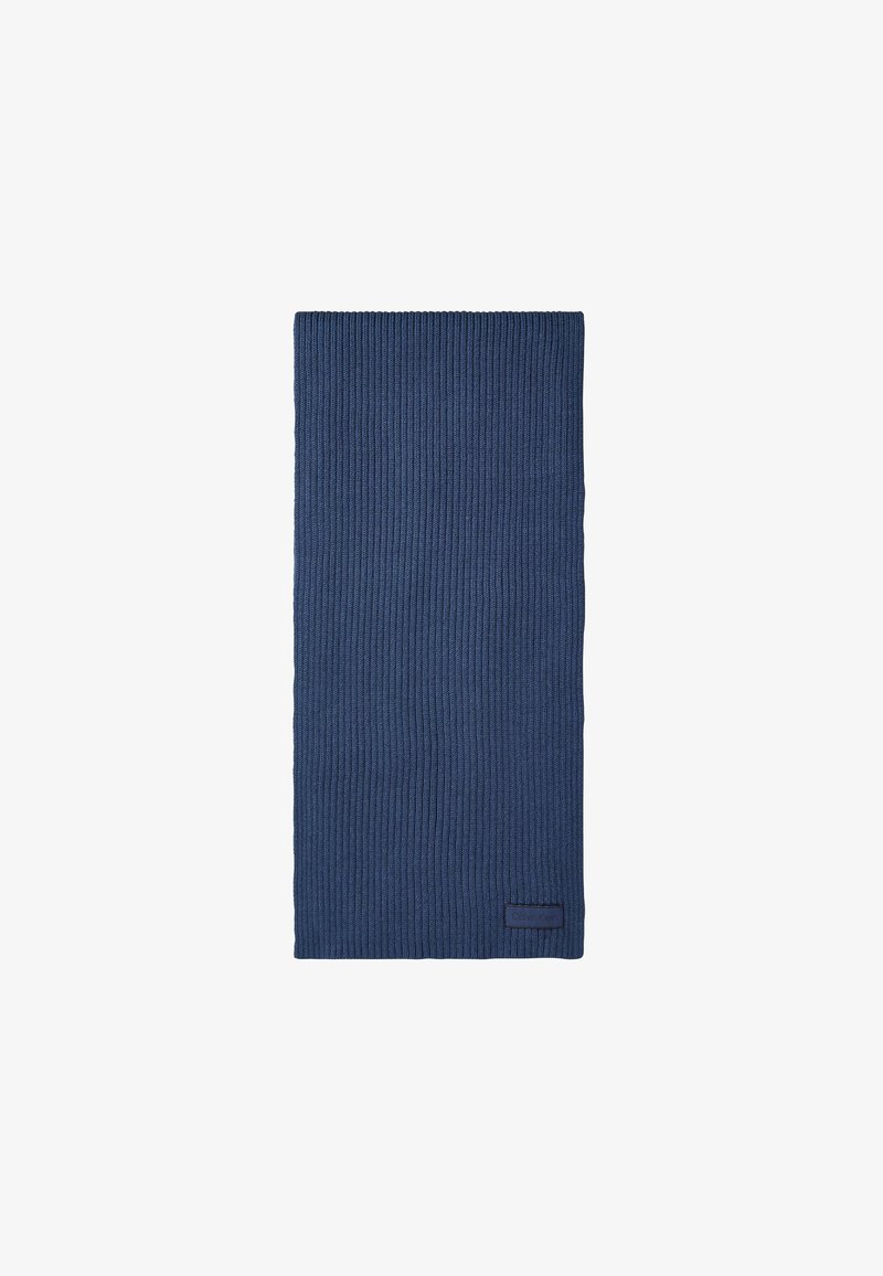 Écharpe en maille côtelée bleu foncé, pliée avec une petite étiquette noire rectangulaire cousue près du bord inférieur.