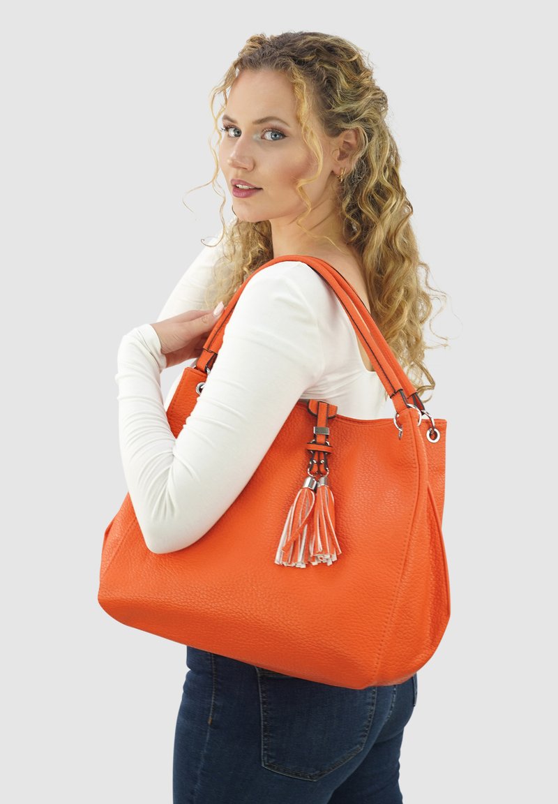 Oranje leren totebag met een gestructureerd oppervlak, zilverkleurige hardware en een decoratieve franje. Voorzien van dubbele schouderbanden voor het dragen.