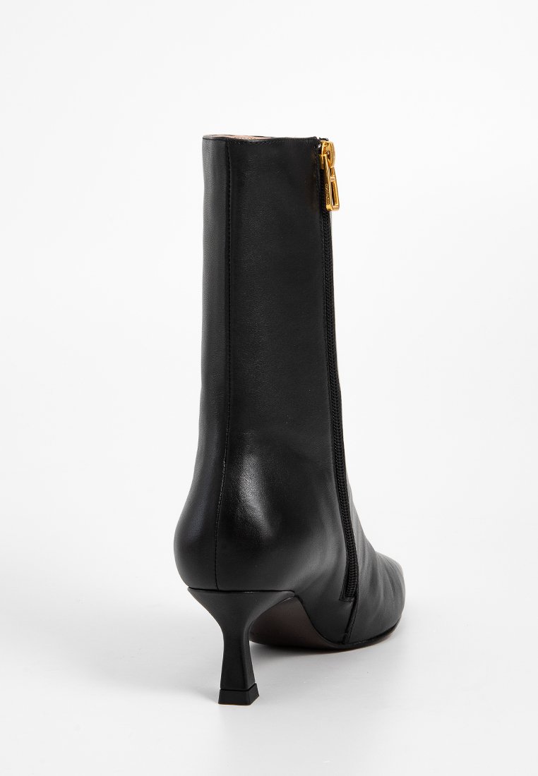 Stivale alla caviglia in pelle nera con un design elegante, punta affusolata, tacco basso e una zip dorata sul lato per un facile accesso.