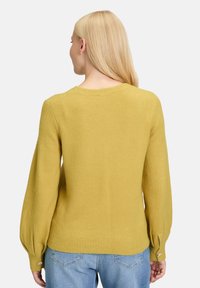 Senfgelbes Sweatshirt mit ribbeltem Saum, rundem Ausschnitt und puffärmeligen, mit Knopfakzenten an den Bündchen. Weiche Textur.