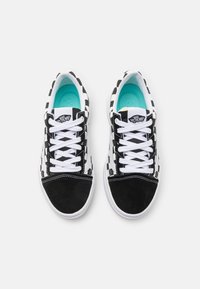Baskets à carreaux noir et blanc avec un embout en daim, des lacets blancs et des semelles intérieures turquoise. Présente un logo Vans sur la languette.