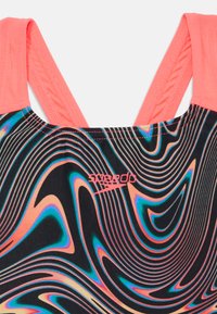 Haut de maillot de bain noir avec des motifs ondulés vibrants en orange, bleu et violet. Présente une encolure et des bretelles roses ; logo sur le côté gauche.