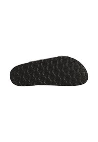 Svart sandal sula med djupt geometriskt mönster, fotograferad från undersidan mot en vit bakgrund.