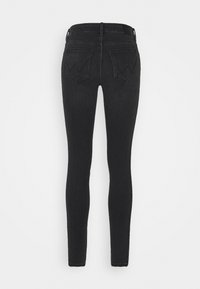 Jeans negros ajustados de mezclilla, con un diseño de cintura alta, estilo de cinco bolsillos y costura en forma de W distintiva en los bolsillos traseros.