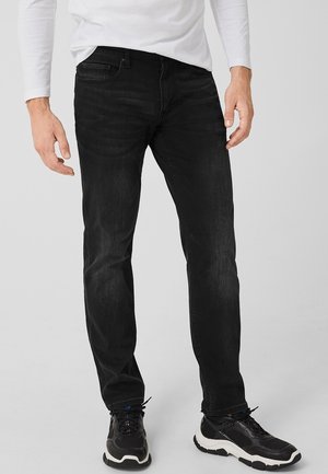 Černé džínové kalhoty z denimu s přímým střihem, mírným vyblednutím, designem s pěti kapsami a šitími detaily, kombinované s černými sportovními botami.