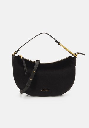 Sac à main noir en forme de croissant avec fermeture éclair dorée, accents dorés, bandoulière réglable et logo "COCCINELLE" à l'avant.