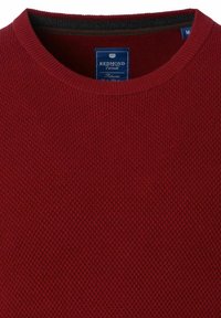 Rot gestrickter Pullover mit Rundhalsausschnitt und gerippten Bündchen. Das eingenähte Etikett innen zeigt "REDMOND Casual" auf blauem Hintergrund mit weißem Text.