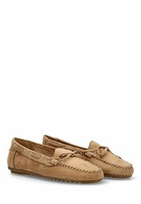 Mocasines de ante en beige con puntera redondeada, costuras decorativas, detalles de cordones y suelas de goma para agarre y comodidad.