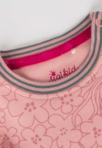 Helles pinkes Hemd mit floralem Muster, kontrastierendem gestreiften Ausschnitt in Pink und Teal sowie einem kleinen Logo über dem Kragen.