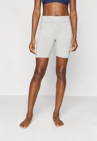 Γκρι ποδηλατικά σορτς από βαμβακερό μείγμα με φαρδιά ελαστική ζώνη μέσης, λεία υφή και μήκος μέχρι τη μέση του μηρού. Γυμνά πόδια.