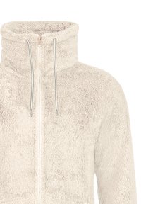 Veste en polaire de couleur crème avec fermeture éclair intégrale, col montant et cordons, fabriquée dans un tissu doux et duveteux pour chaleur et confort.