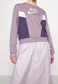 Nike sweatshirt i lavendel med färgblockeringsdesign; med lila och rosa accenter, rund halsringning och ribbade ärmslut.