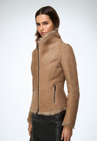 Veste en cuir marron clair avec un col montant, fermeture éclair et deux poches latérales ; dotée d'une bordure en fausse fourrure au niveau du col et de l'ourlet, texture lisse.