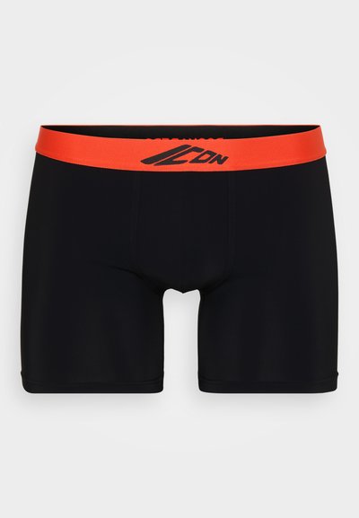 Juodi bokso šortai su kontrastinga oranžine juostos dalimi. Pasižymi lygiu paviršiumi, ant juostos yra atspaustas logotipas, ir jie yra prigludusių formos.
