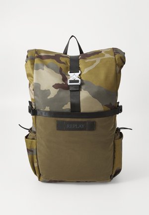 Zaino mimetico in verde, marrone e grigio con design a roll-top, chiusura con fibbia in metallo e spallacci regolabili; presenta una tasca laterale e branding.