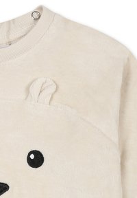 Felpa color crema con una texture morbida, caratterizzata da un design con faccia di orso, occhi ricamati e orecchie in rilievo sulla parte anteriore.