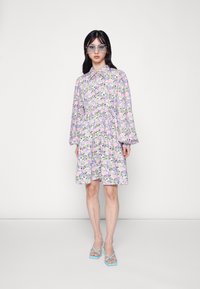 Vestido floral roxo com mangas longas, gola, cintura franzida e sandálias de tiras azul claro. Óculos transparentes com detalhes em metal.