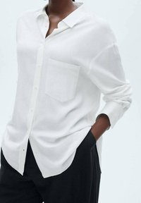 Witte lange mouwen shirt van lichtgewicht materiaal, met een button-down kraag en een borstzak. De pasvorm is los en ontspannen.