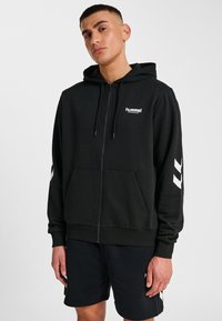 Zwarte rits-hoodie van een katoenmix, met een voorkraag, verstelbare capuchon en wit logo en strepen op de mouwen.