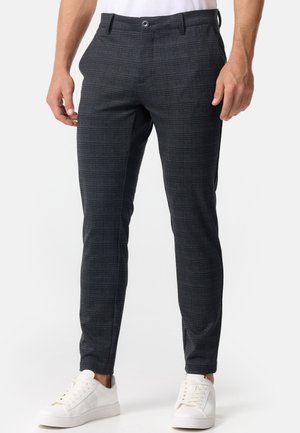 Pantalones de cuadros grises confeccionados en tejido entrelazado, con un ajuste slim, frente plano y cierre de botón, combinados con zapatillas blancas.
