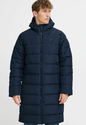 Navy blue puffer coat with a high collar, horizontal quilted design, and zip closure. Features side pockets and a relaxed fit.
