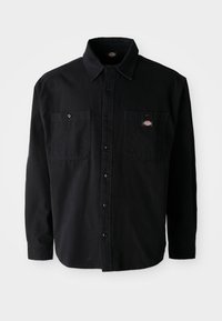 Black long-sleeve button-up shirt with two chest pockets and a logo patch. Made of a sturdy fabric with a smooth texture and classic collar.