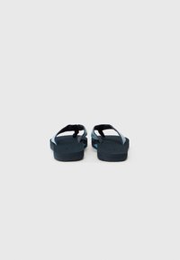 Sorte flip-flops med teksturerte stropper som har et blått og grønt spraglete design, tykke gummisåler og en buet fotbed.