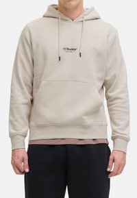 Beige Kapuzenpullover aus Baumwollmischung, mit einer Fronttasche, verstellbaren Kordeln und einem kleinen Logo auf der Brust. Gerippte Bündchen und Saum.