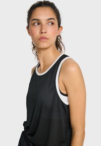 Black athletic tank top with a breathable mesh fabric, white accents on the neckline and armholes, loose fit, and a textured pattern.