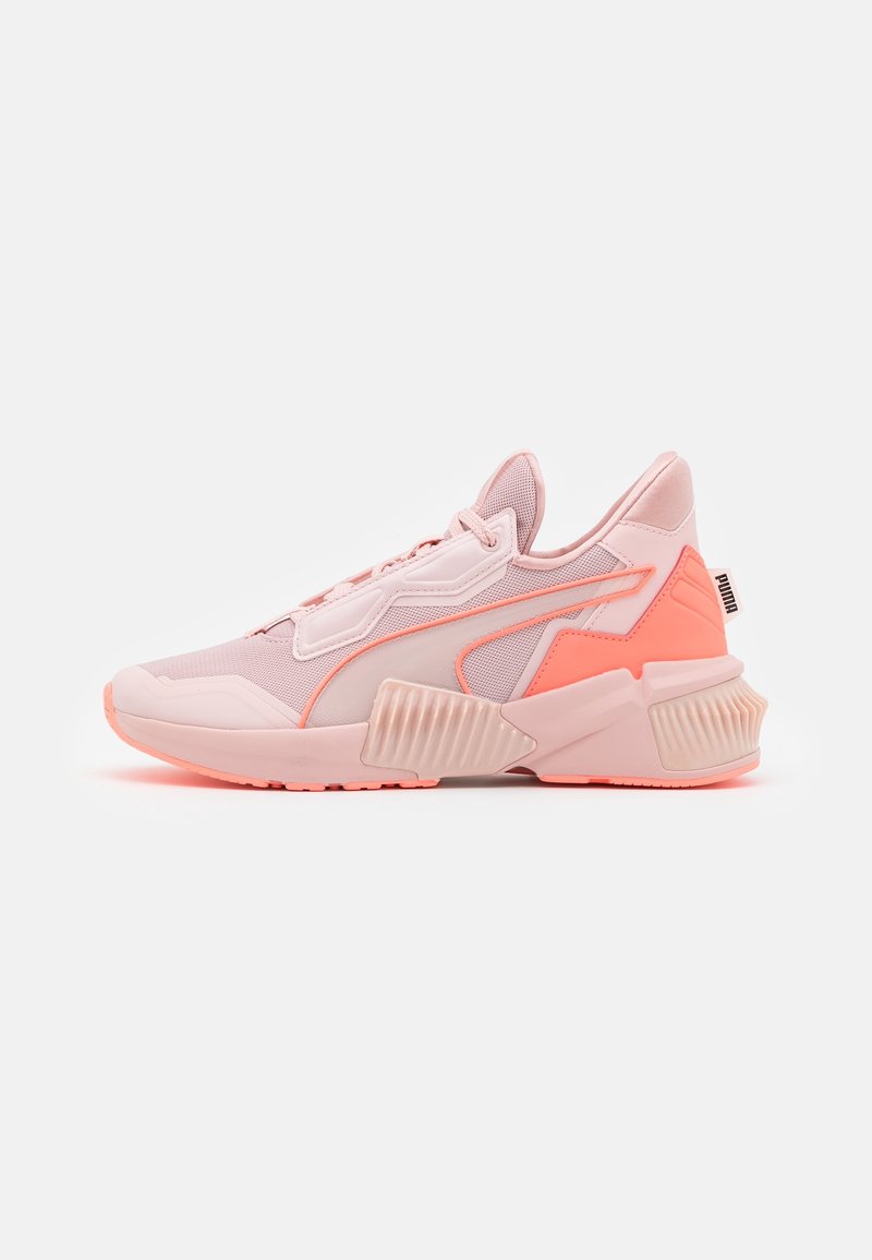 Zapatillas deportivas de color rosa claro con una parte superior de malla texturizada, acentos en naranja neón, suela de goma gruesa y elementos de diseño geométrico distintivos.