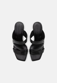 Chanclas negras con puntera cuadrada, que cuentan con dos correas anchas y una plantilla texturizada. Material de cuero elegante con un diseño minimalista.