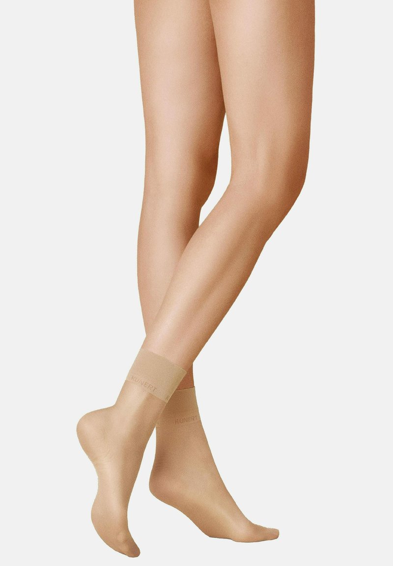 Durchsichtige Nylon-Socken bis zum Knöchel in Beige, mit glatter Textur, dezentem Glanz und einem weichen Bund, auf dem der Markenname "kunert" aufgedruckt ist.