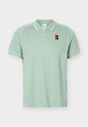 Polo vert clair à manches courtes avec col et bords des manches rayés blancs, avec un petit écusson coloré du logo Nike sur la poitrine gauche.