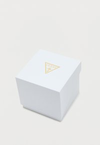 Caixa branca texturizada com um logótipo triangular dourado no topo. A caixa apresenta um design limpo e simples, com uma tampa segura.