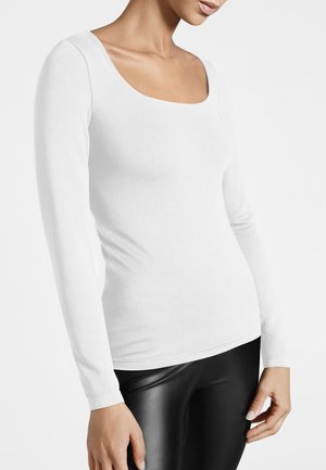 Weißes Langarmshirt mit Rundhalsausschnitt, taillierter Passform und glatter Textur, kombiniert mit schwarzen glänzenden Leggings.