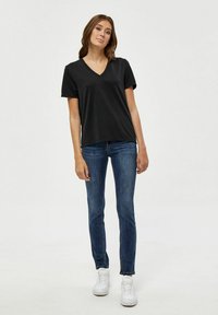 Schwarzes V-Neck T-Shirt mit kurzen Ärmeln, getragen mit blauen Slim-Fit-Jeans und weißen Sneakers. Glattes Material und bequeme Passform.
