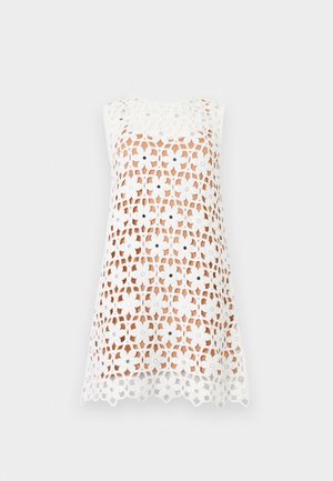 Vestido mini blanco sin mangas con un gran patrón floral de encaje sobre un forro nude, con recortes en forma de flores y un dobladillo con borde festoneado.