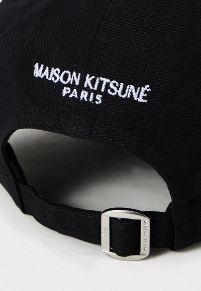 Black fabric cap featuring white embroidered "MAISON KITSUNÉ PARIS" text and a metal adjustable strap buckle with brand engraving.