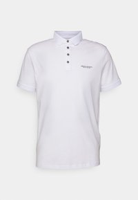 Vit pikétröja i bomull med klassisk krage, treknappsförslutning och kontrasterande blå manschetter. Har en liten logotyp på bröstet.