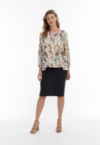 Blusa a paisley multicolore con maniche ampie, abbinata a una gonna a tubino nera e sandali con tacco blocco color taupe.