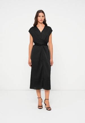 Black midi dress with a wrap design, short cap sleeves, V-neckline, and a fitted waist, paired with black strappy heels. Smooth fabric.