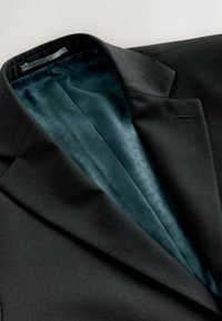 Donkergrijze blazer met gestructureerde stof, met een tealkleurige binnenvoering die een subtiel geometrisch patroon vertoont en een notched reverskraag.