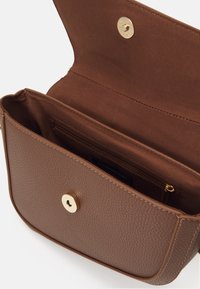 Borsa in pelle marrone con texture e hardware dorato. Presenta una chiusura magnetica e una tasca interna con zip. Foderata in tessuto.
