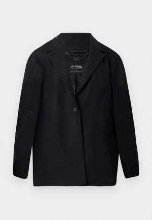 Blazer preto feito de tecido reciclado, com lapela de recorte, fecho de um botão e mangas compridas. Superfície texturizada com partículas de fiapos visíveis.