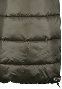 Partie de veste matelassée vert olive foncé avec des surpiqûres horizontales et une étiquette noire près de l'ourlet inférieur indiquant les détails de la marque.