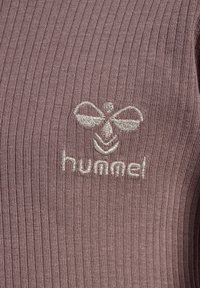 Fioletowa prążkowana tkanina z wyszywaną srebrną logo pszczoły oraz nazwą marki "hummel" poniżej. Tekstura jest gładka i jednolita.