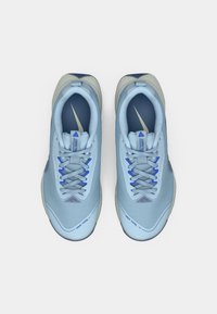 Šviesiai mėlyni ir pilki sportiniai bėgimo bateliai su raišteliais, matomais Nike logotipais ir paminkštintomis vidpadžiais ant balto fono.