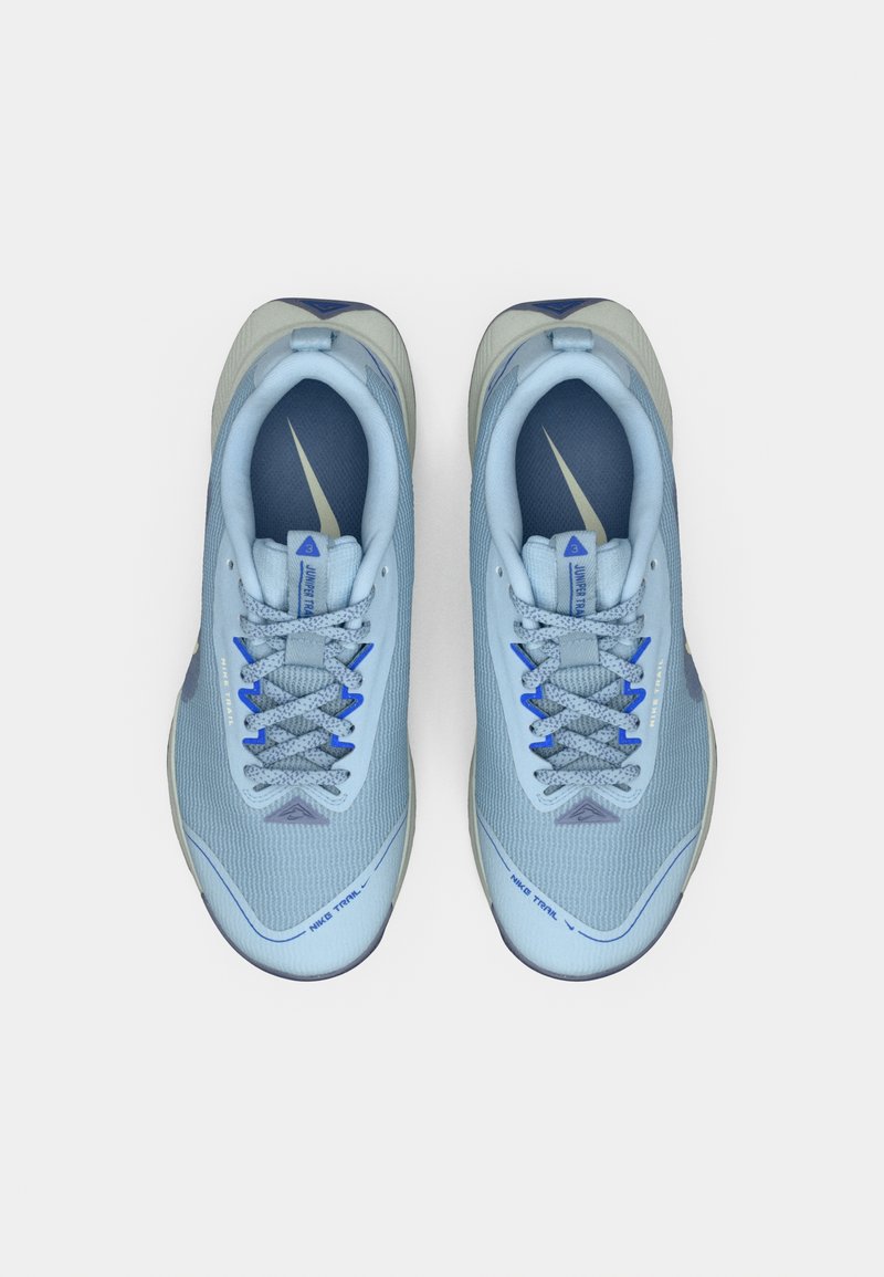 Un par de zapatillas deportivas de trail de color azul claro y gris con cordones, logotipos de Nike visibles y plantillas acolchadas sobre un fondo blanco.